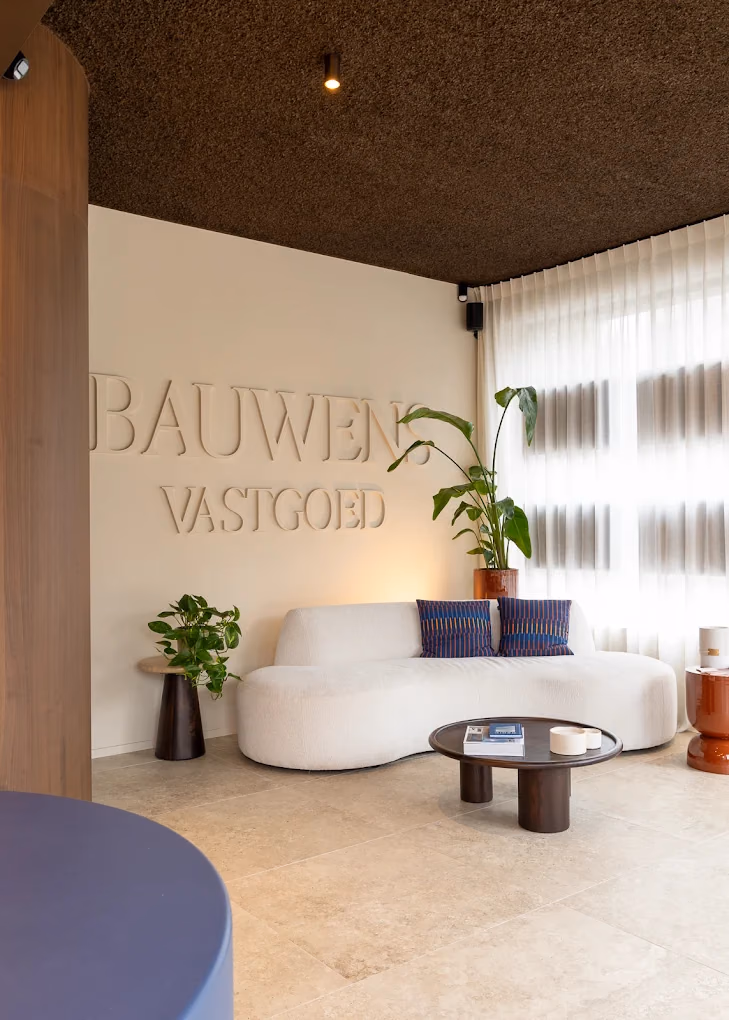 The waiting area at Bauwens Vastgoed, with the agency name in relief on the wall