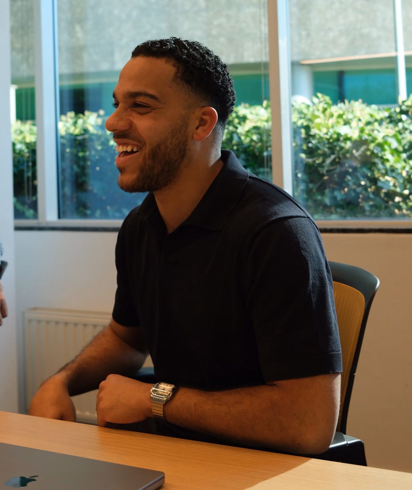 A smiling Ulvio colleague at the meeting table during a session with a client, laptop on the table.